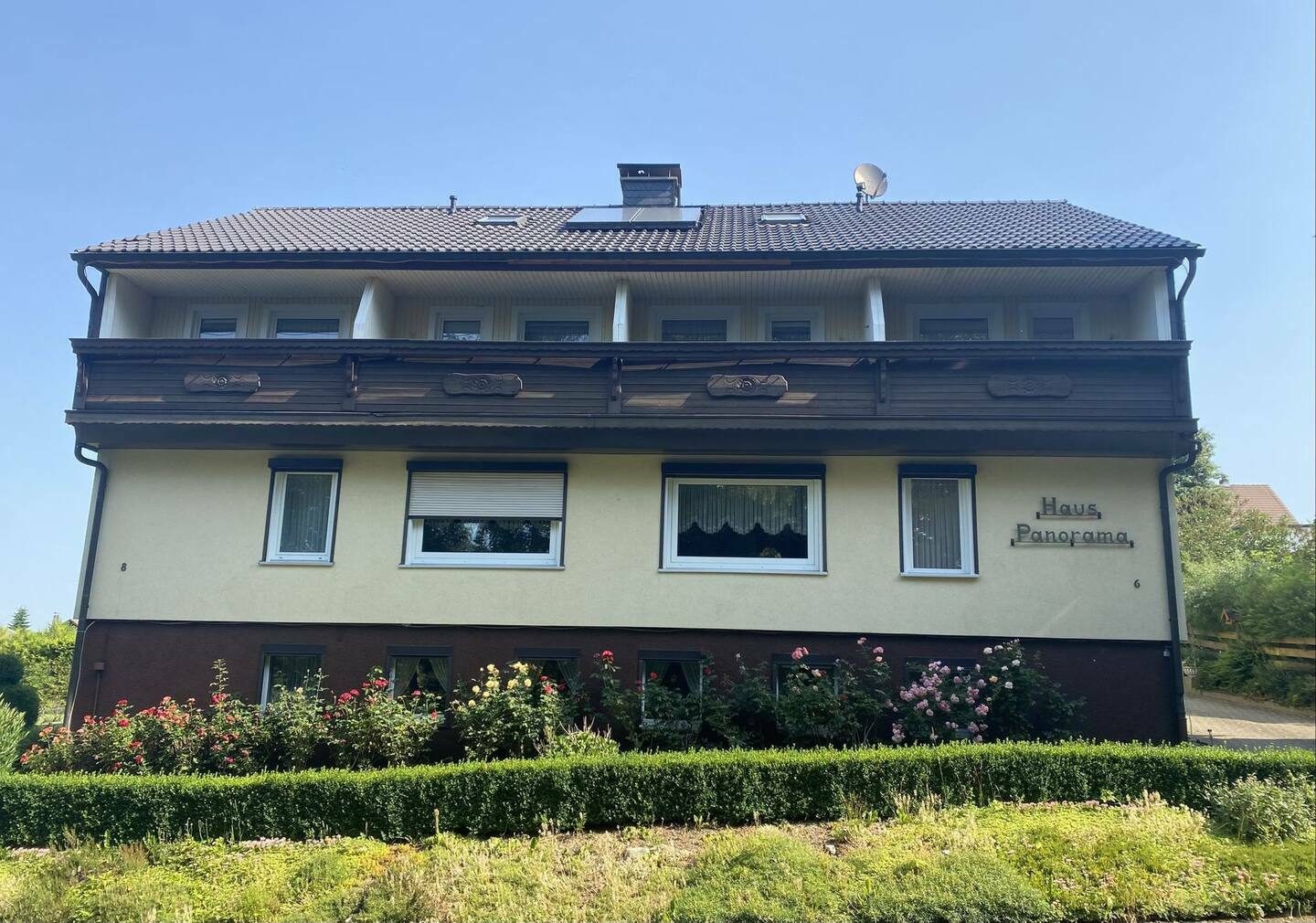 Haus Panorama im Sommer mit Balkonen und Rosen