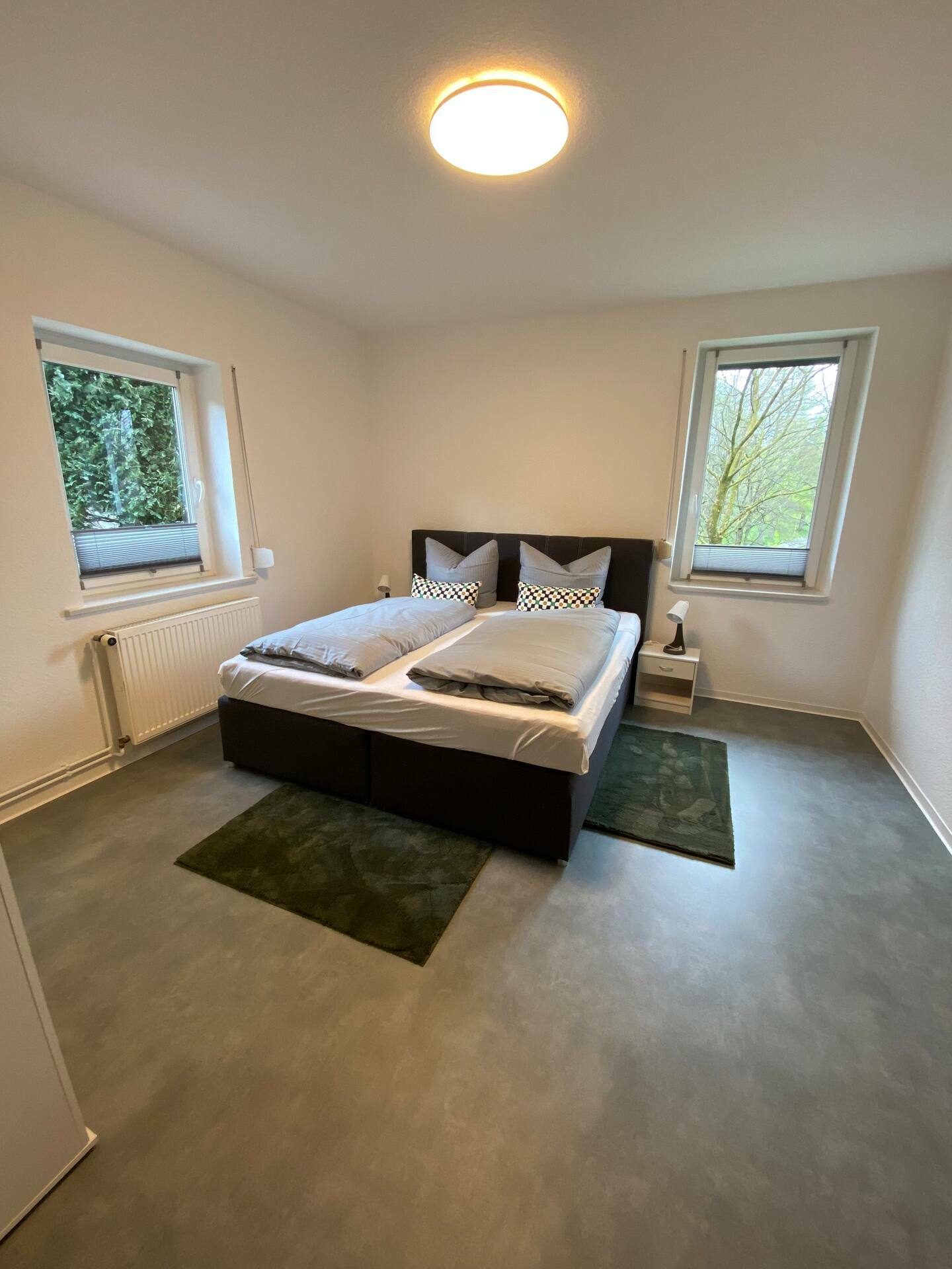Schlafzimmer mit Doppelbett und zwei Fenstern