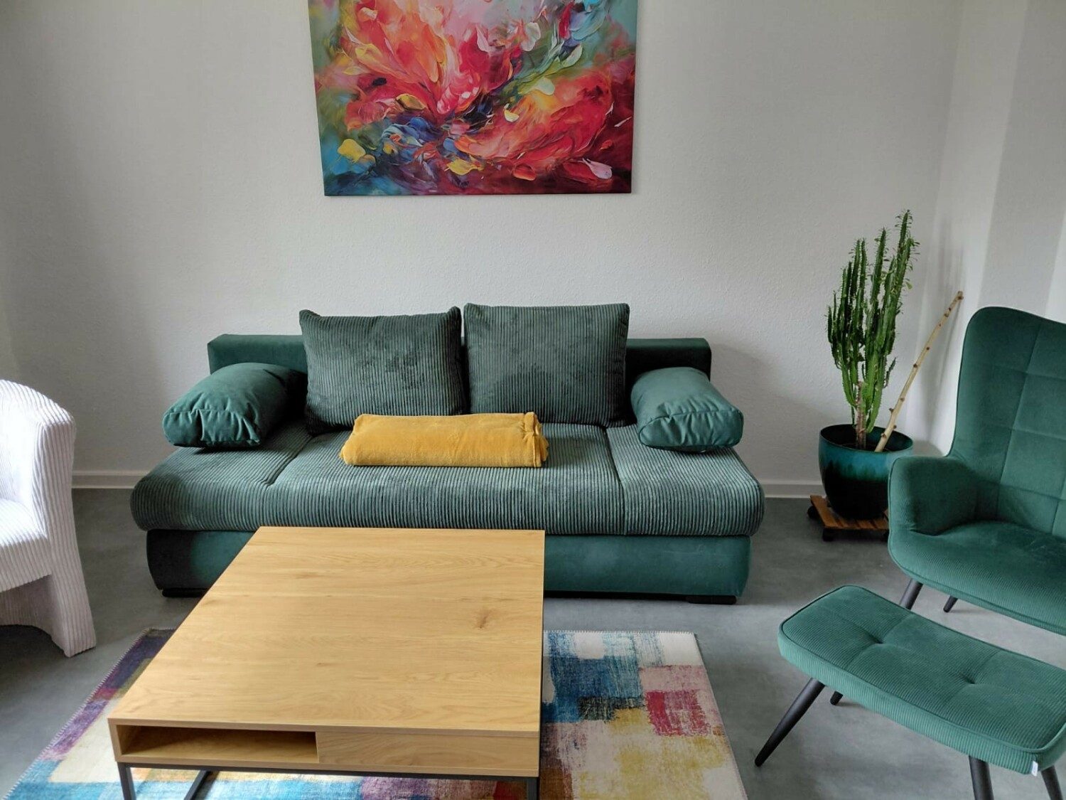 Wohnbereich mit grünem Sofa und buntem Teppich